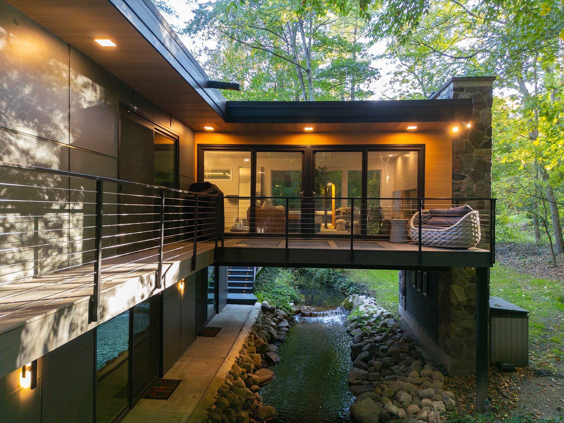 Beige house with two wooden decks, green lawn, blue sky.