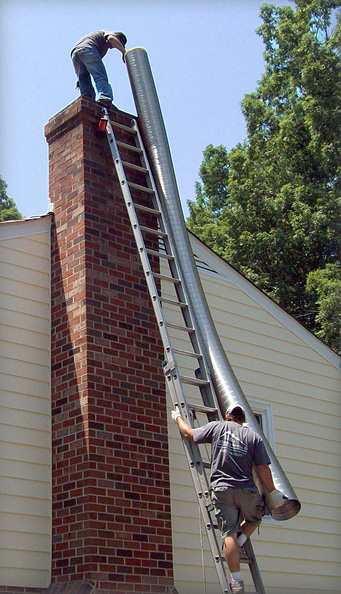 A man on a ladder is working on a chimney