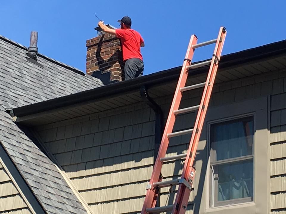 A man standing on top of a roof next to a ladder