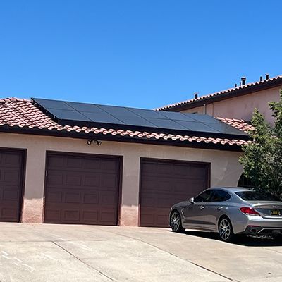 A car is parked in front of a garage with solar panels on the roof