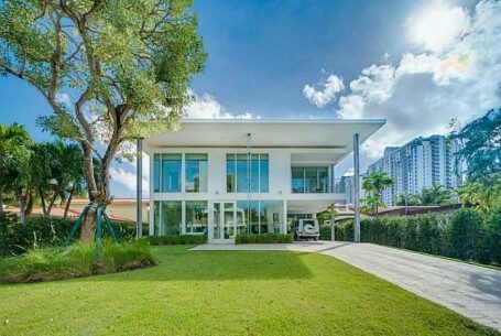A large white house with a lot of windows is sitting on top of a lush green lawn