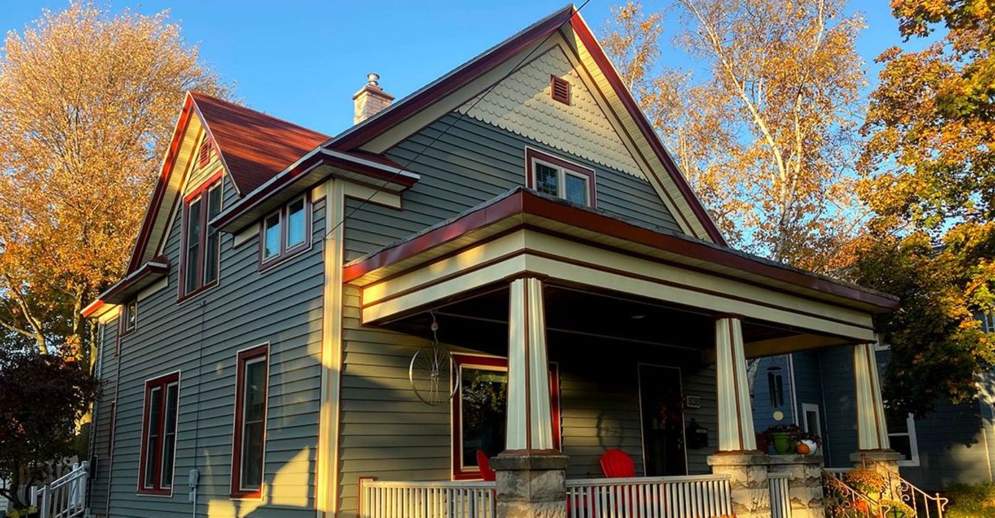 A large house with a porch and a red roof