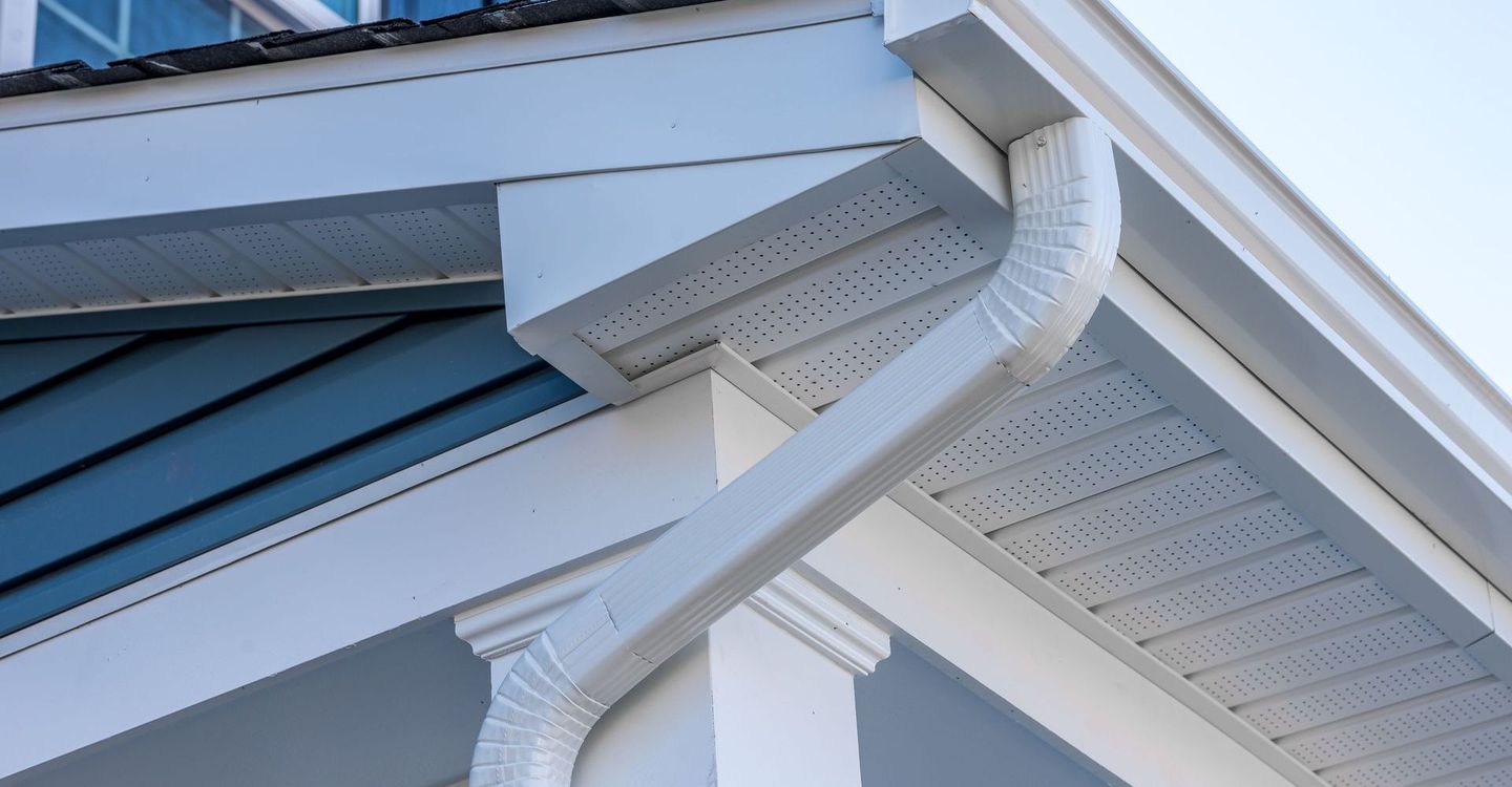 A close up of a white gutter on the side of a house
