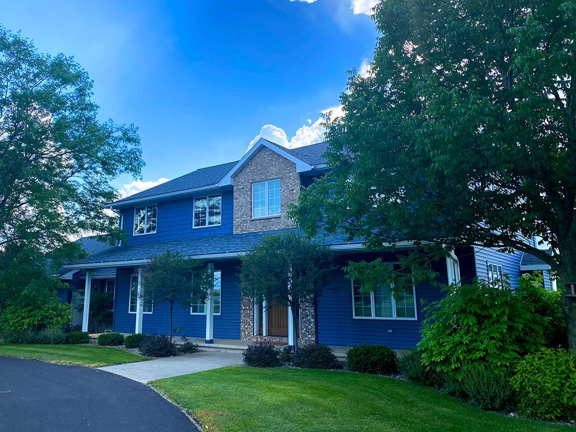 A large blue house with a lot of windows and trees in front of it.