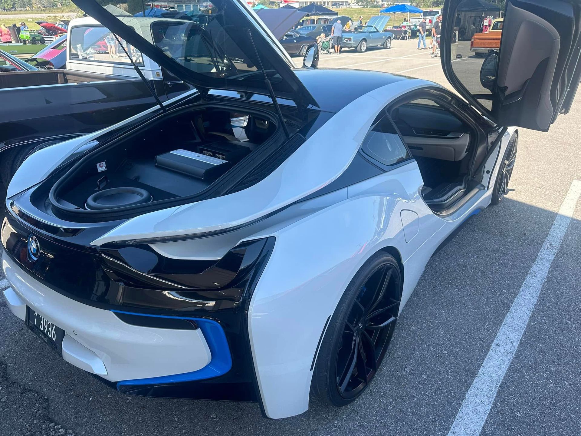 A white and black sports car with the hood open is parked in a parking lot.