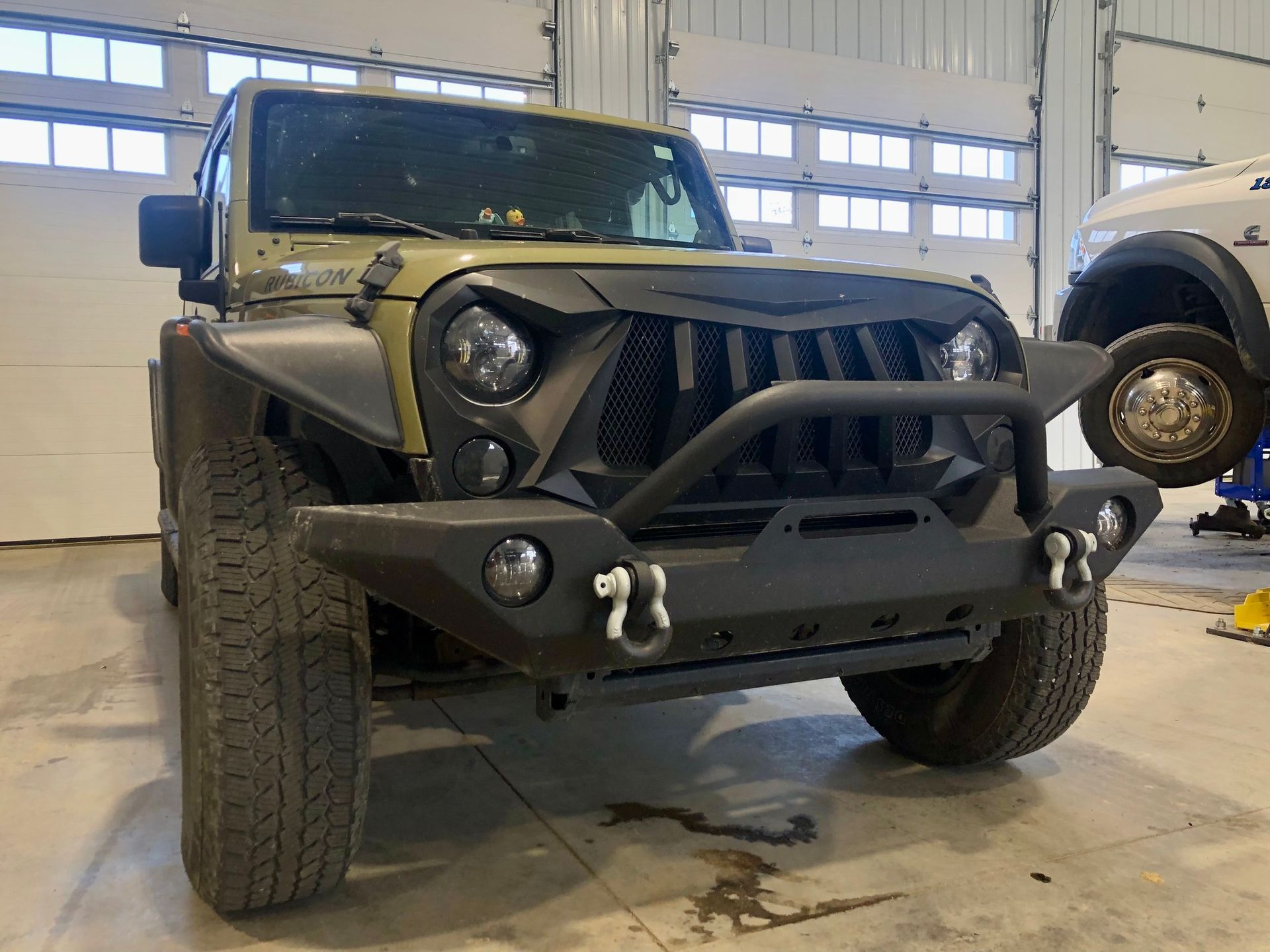 A jeep is sitting on a lift in a garage.