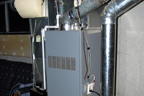 an heating system is sitting in a basement next to a wall .