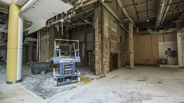 An empty building with a blue scissor lift in the middle of it.