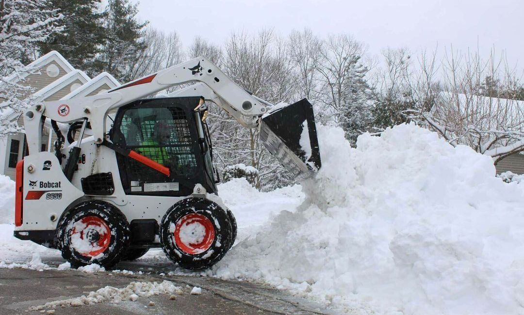 A snow plow is driving down a snow covered road.
