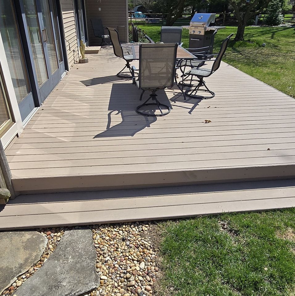 A deck with a table, chairs, and grill. Steps lead down to a grassy yard.
