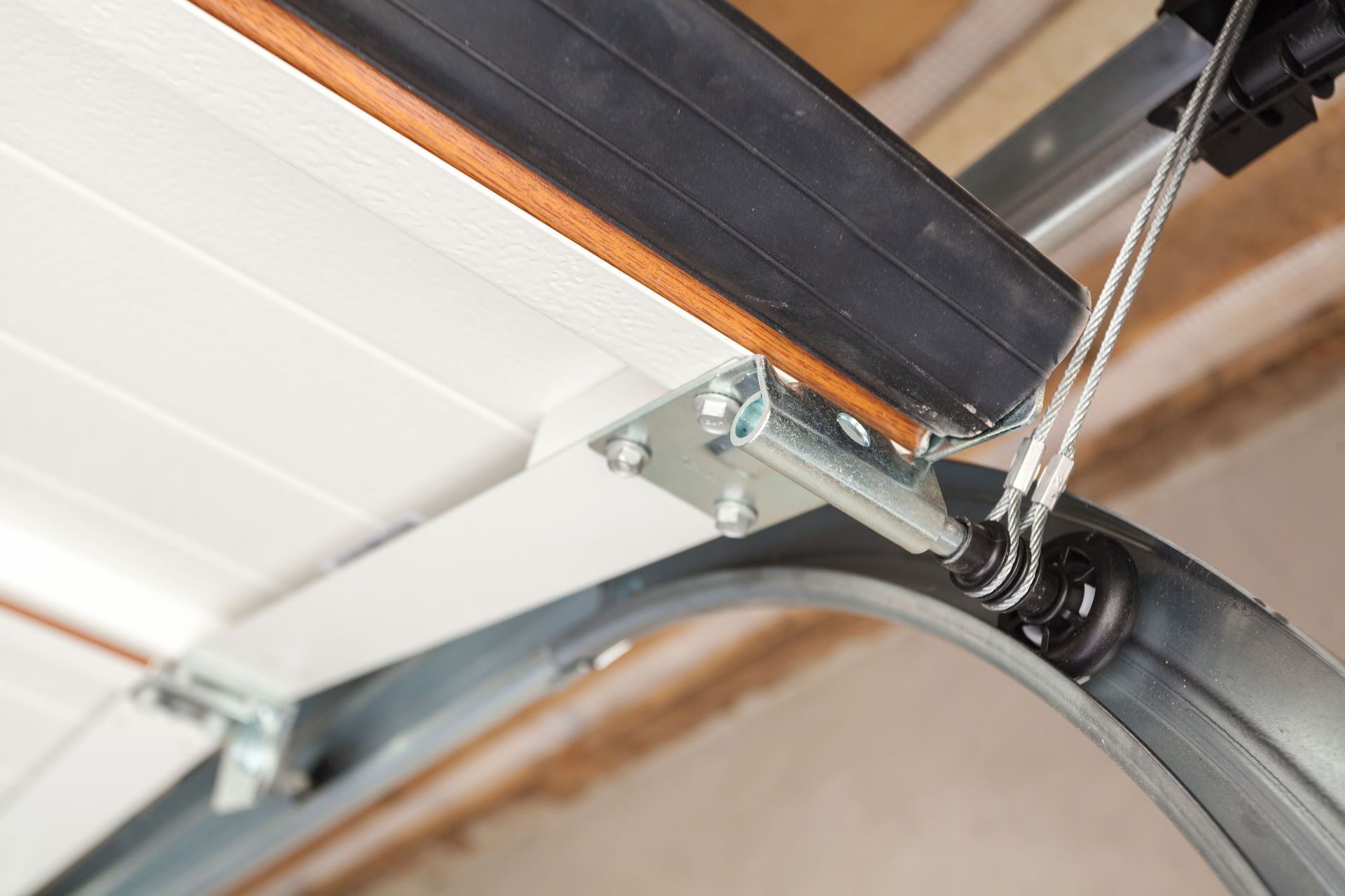 Close-up of a garage door track, roller, and spring mechanism mounted to the ceiling.