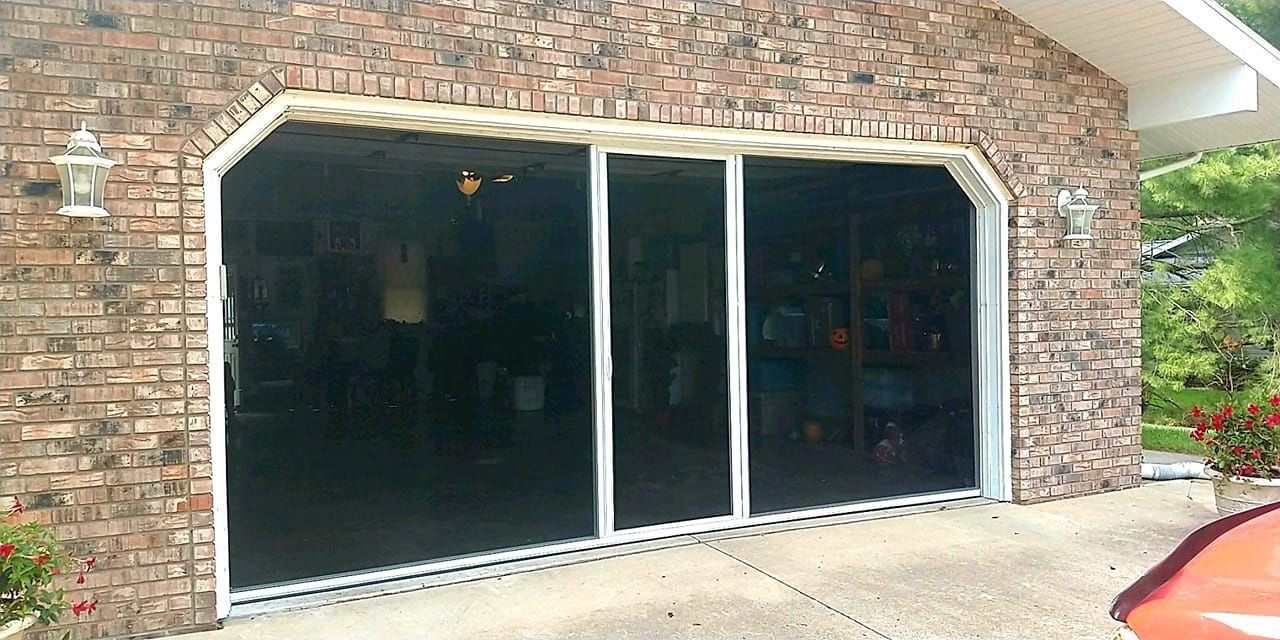 Brick building entrance with large dark sliding glass doors and a stone archway