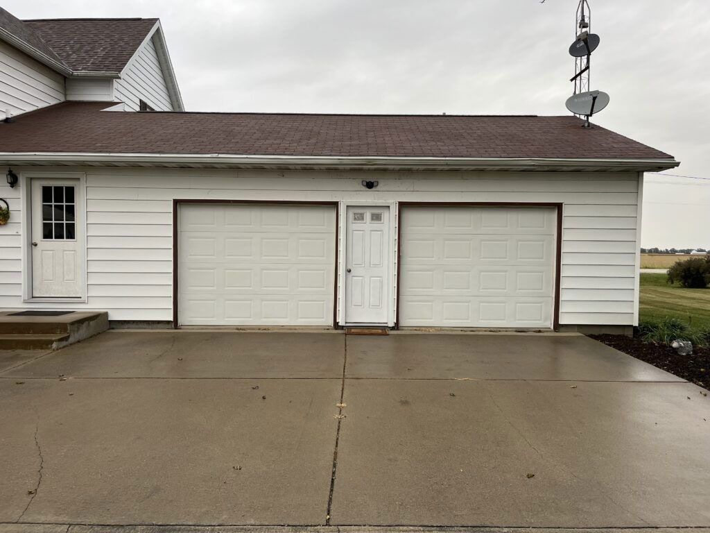 Two-car garage with white doors and a driveway in front of a house