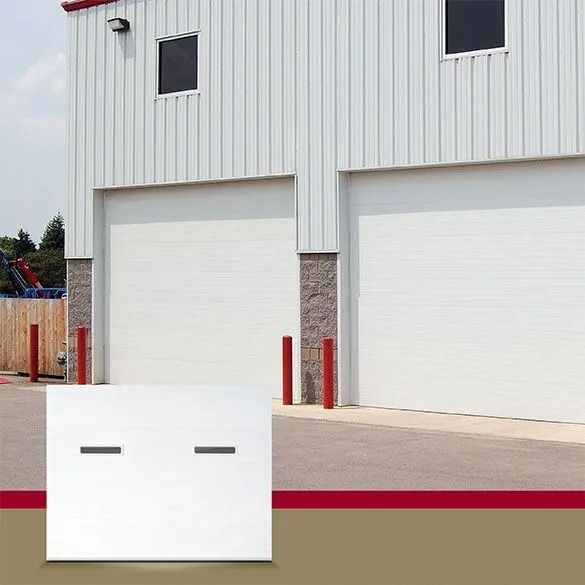 Industrial building with white roll-up garage doors and red bollards, viewed from the parking lot