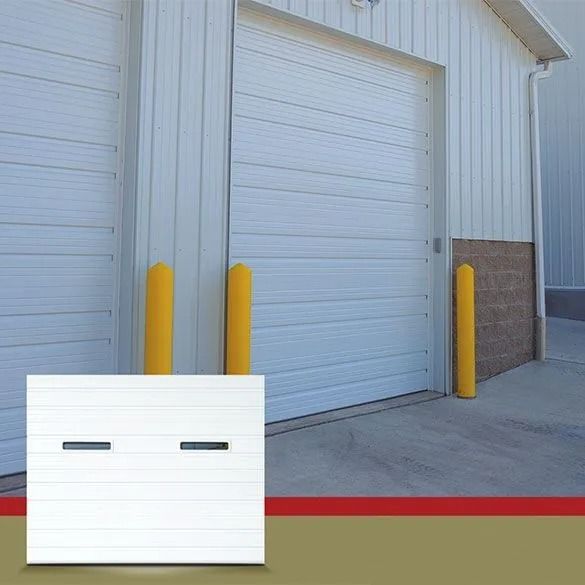 Industrial warehouse loading dock with white roll-up doors, yellow bollards, and a red curb line.