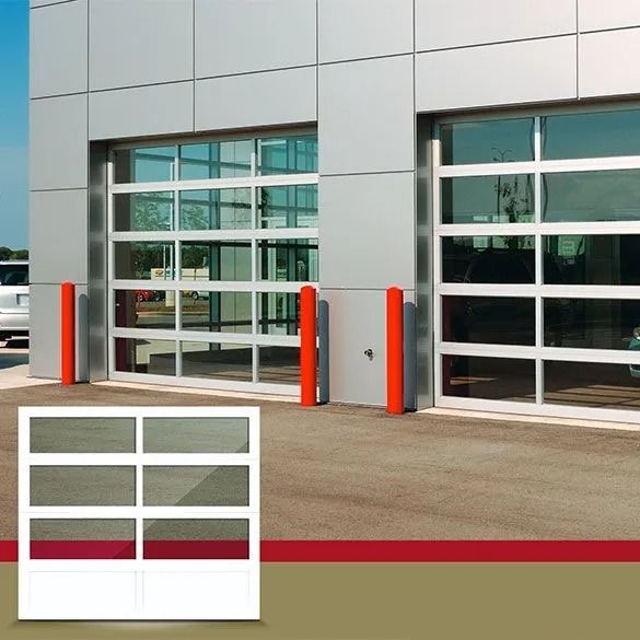 Modern glass building exterior with two red bollards and white-framed garage doors