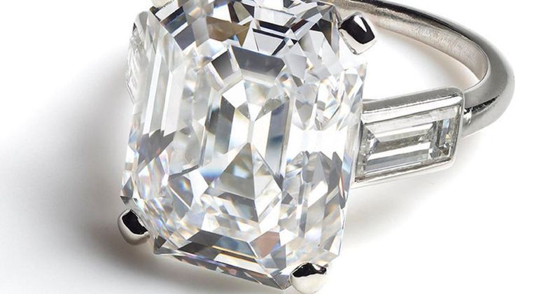 A close up of a diamond ring on a white surface.