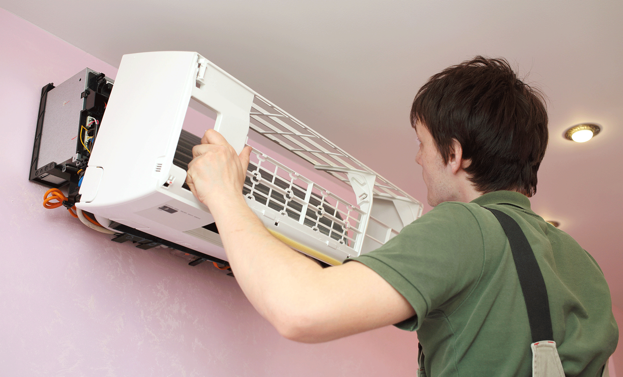 A man is fixing an air conditioner on a wall.