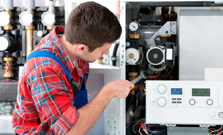 A man is working on a boiler with a wrench.