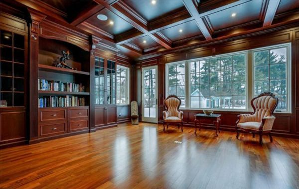 A living room with hardwood floors , chairs , a table and a large window.