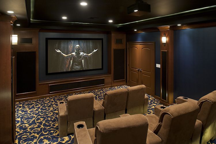 A home theater with a large screen and brown chairs