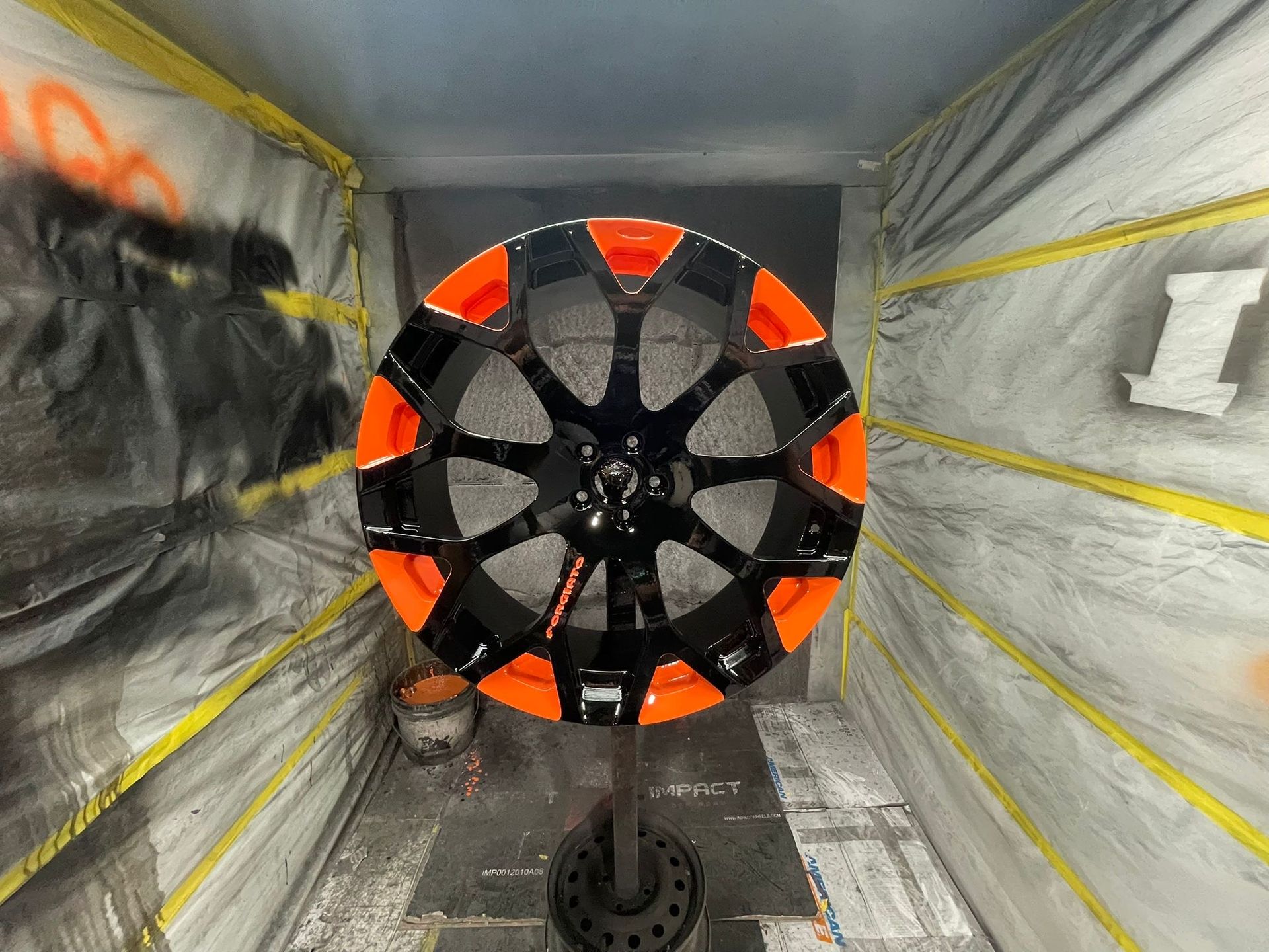 Black and orange car rim in a spray booth.