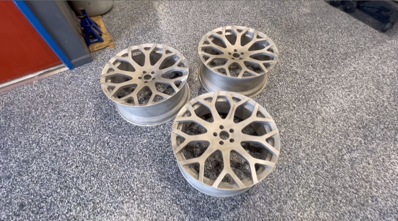 Three silver car wheels on a sparkly gray floor.