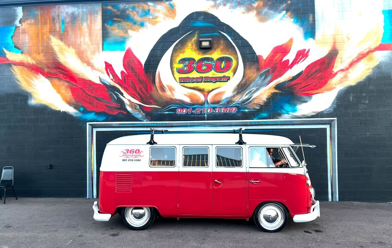 Red and white vintage VW bus parked in front of a mural; building with a flower-like painting.