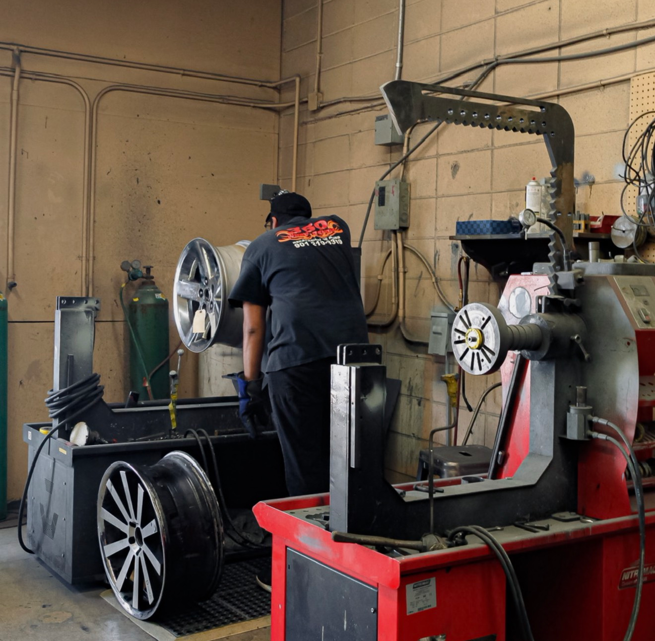Mechanic balancing a car wheel in a garage.
