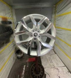 Silver alloy car wheel with five lug nuts and a modern spoke design - after