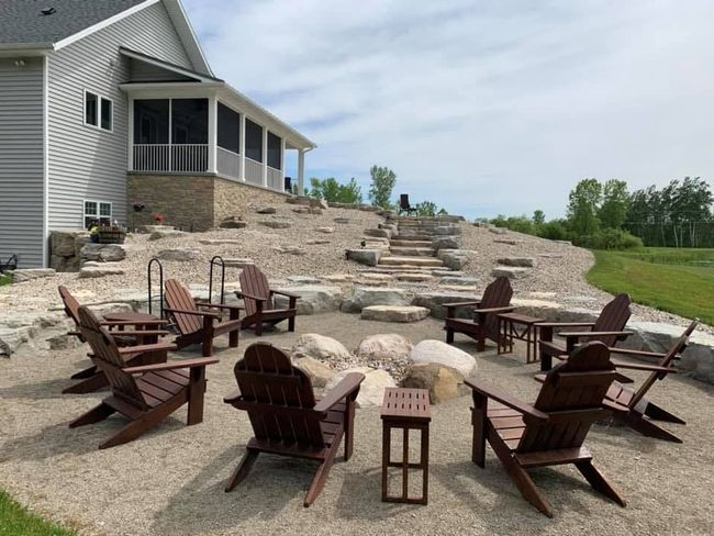 A group of chairs are sitting around a fire pit in front of a house.