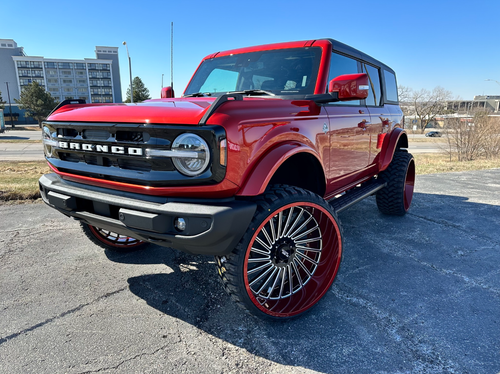 White sports car with black wheels and red brake calipers parked outside a building.