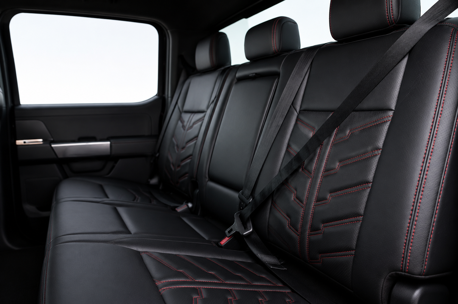 Black leather car back seat with red stitching and two headrests, viewed from inside the vehicle