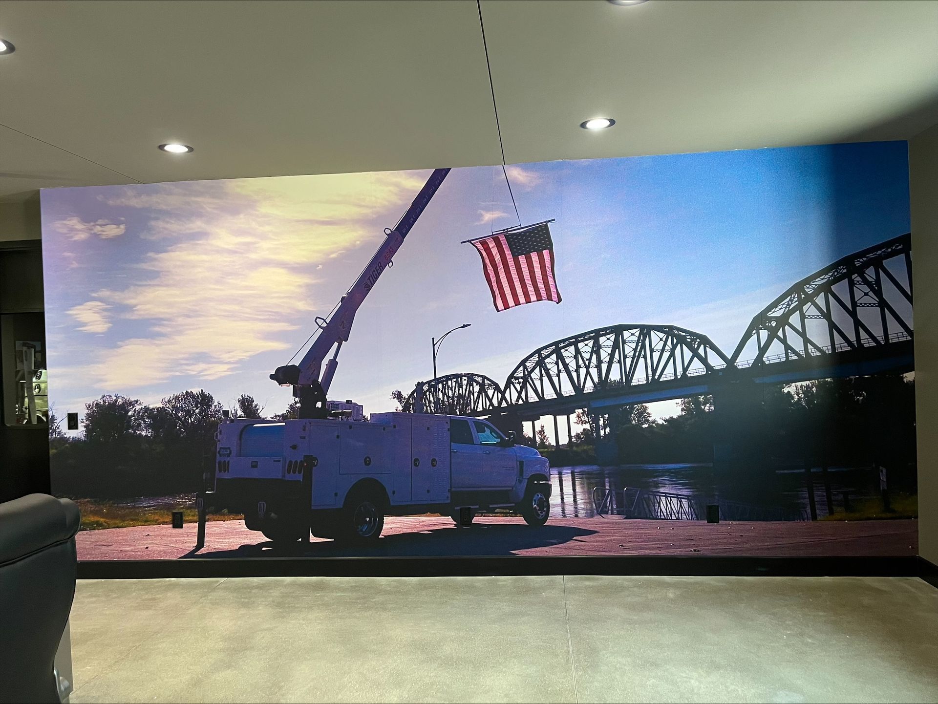 Red fire truck with American flag at sunset near a river and steel bridge