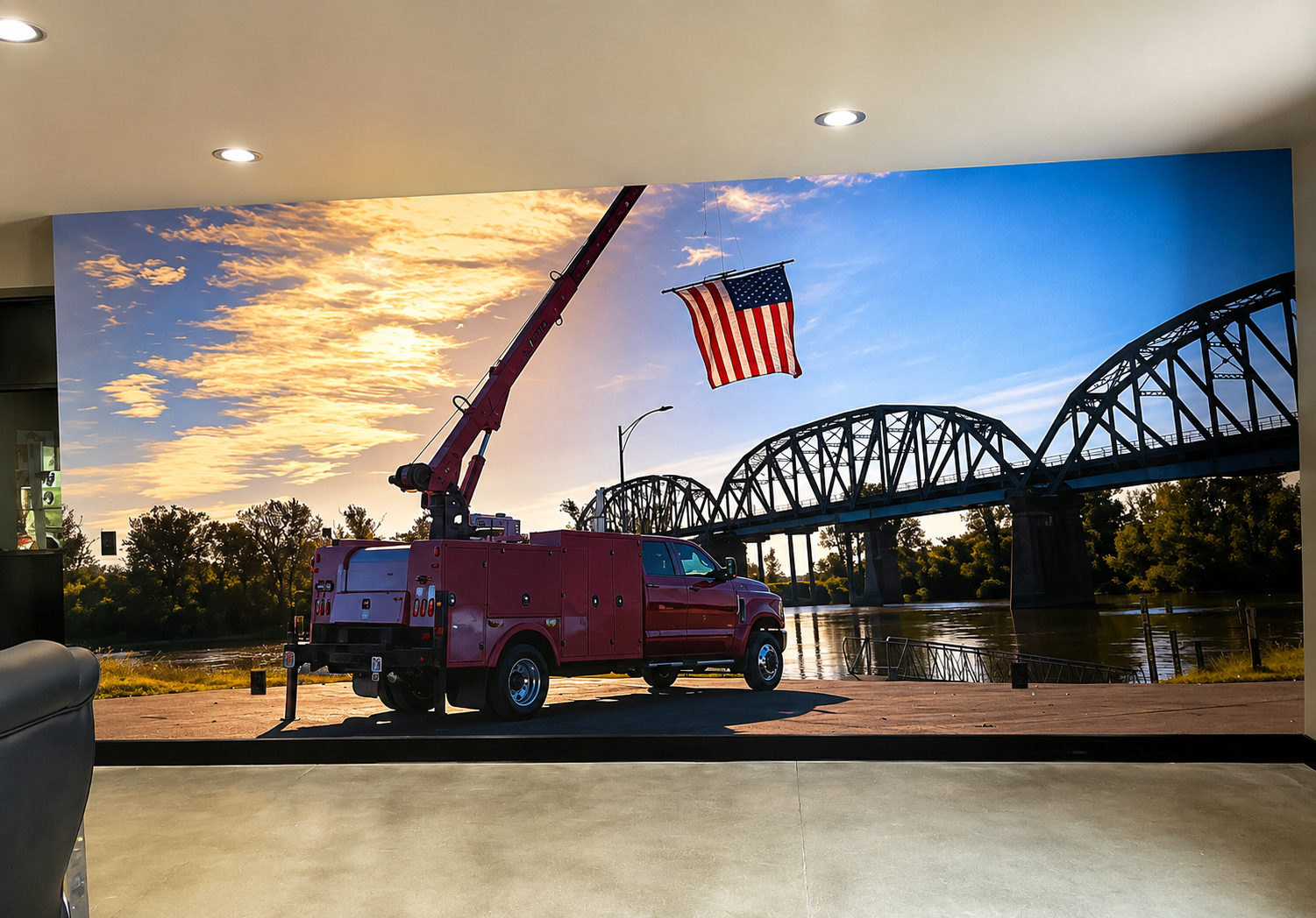 Red fire truck with American flag at sunset near a river and steel bridge