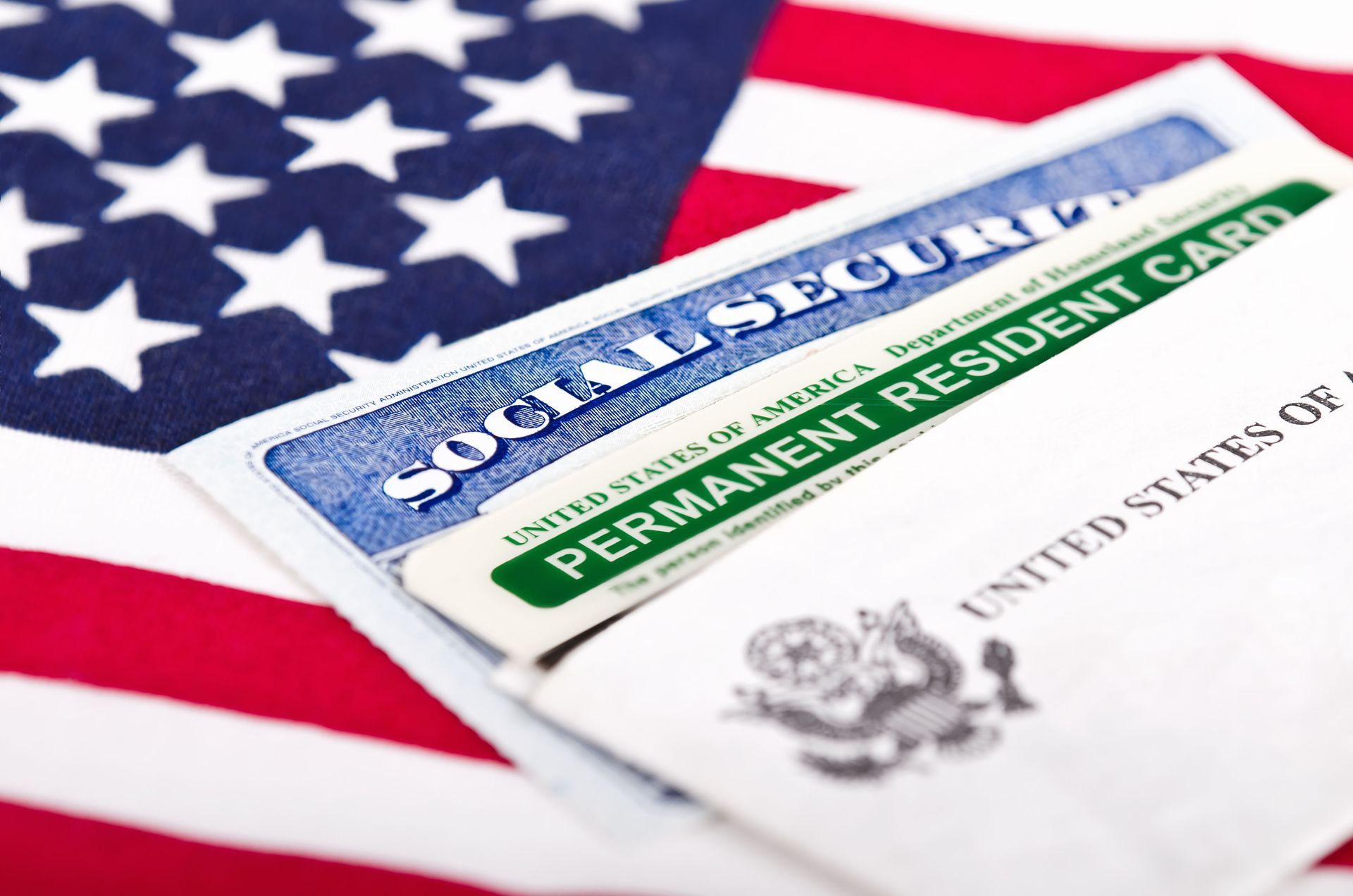 A social security card and a permanent resident card on top of an American flag