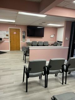 A waiting room with chairs and a television on the wall.
