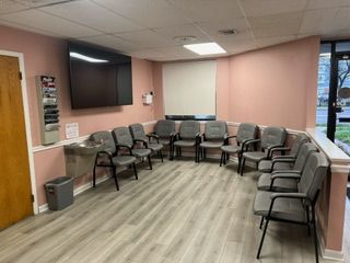 A waiting room with a lot of chairs and a flat screen tv.