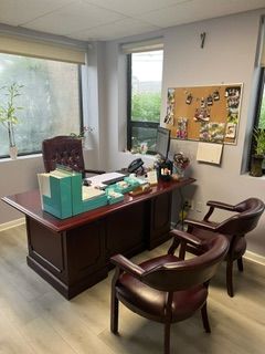 A office with a desk , chairs and a cork board on the wall.