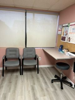 A waiting room with three chairs and a desk.