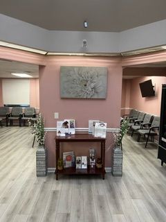 A waiting room with a table and chairs and a painting on the wall.