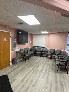 A waiting room with chairs and a television on the wall.