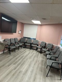 A waiting room with a lot of chairs and a flat screen tv.