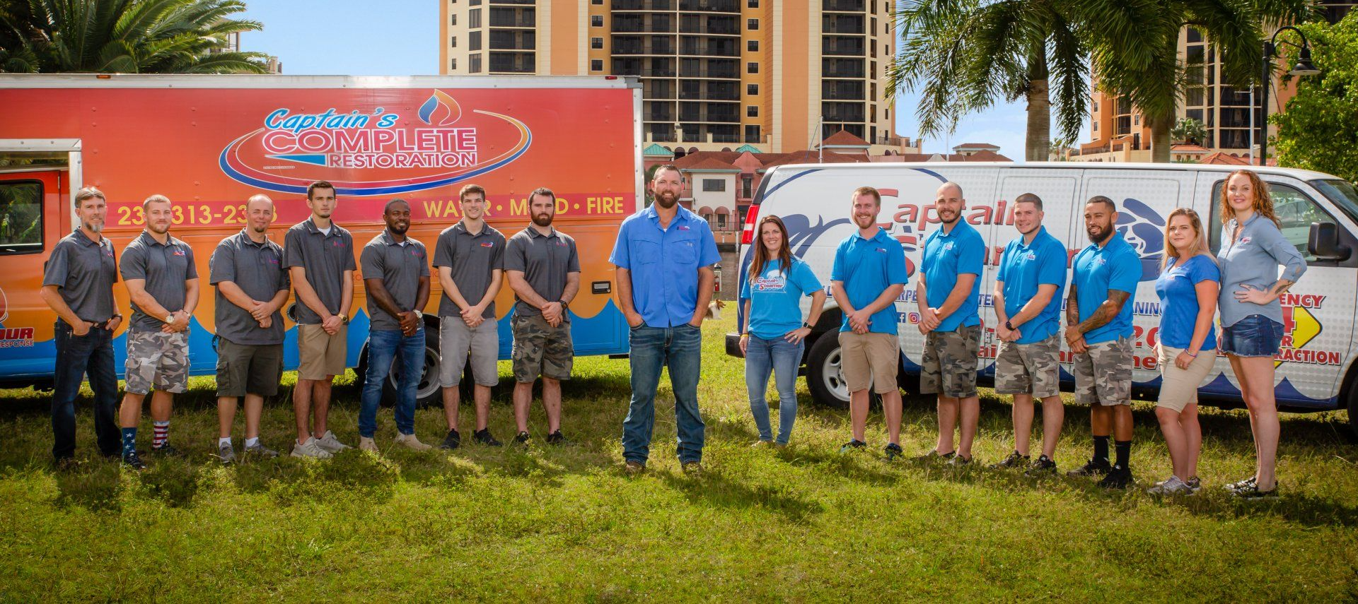 Group of people in front of two company vehicles with company logos on them.