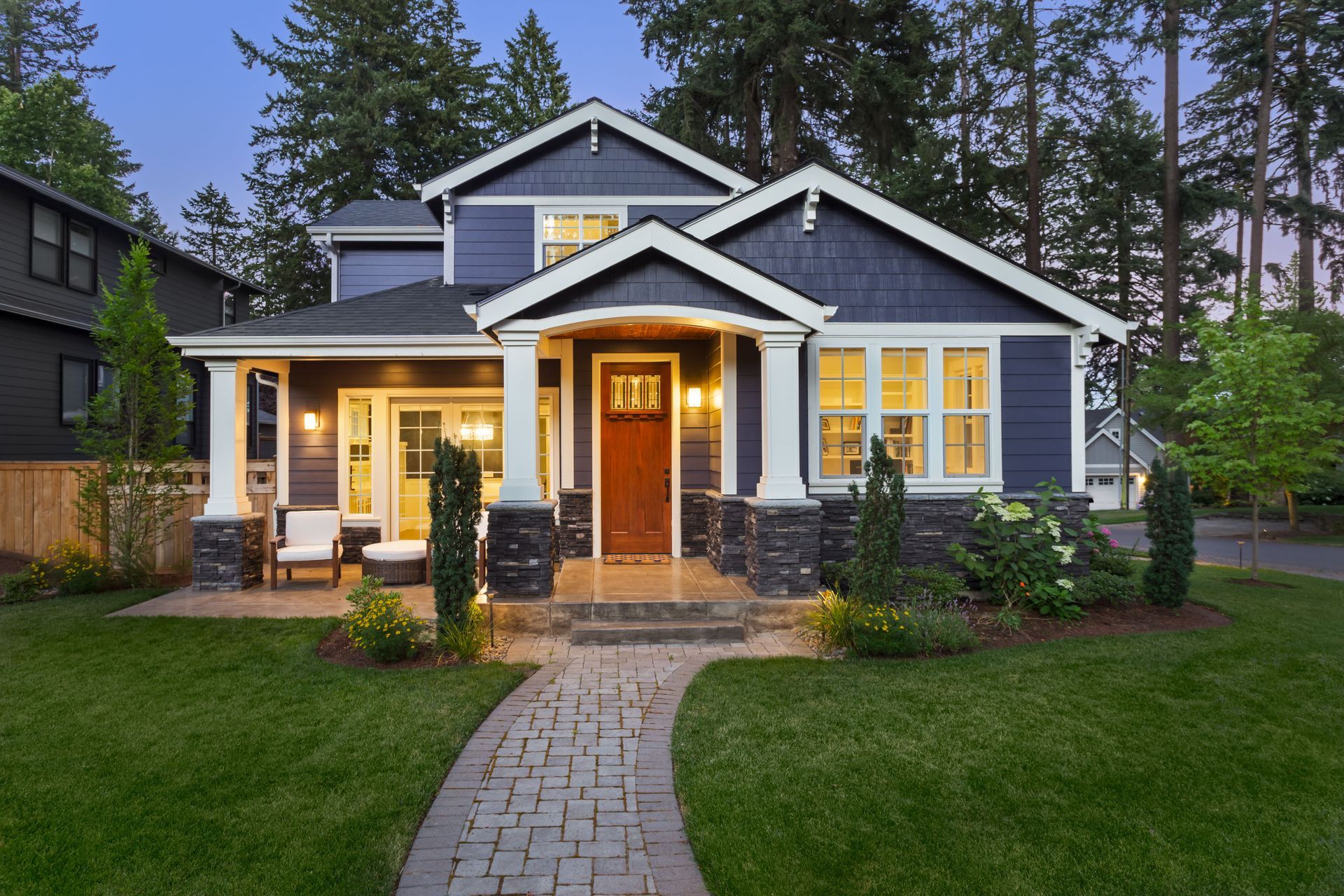 Blue house with white trim, a red door, and a brick walkway leading to the entrance.