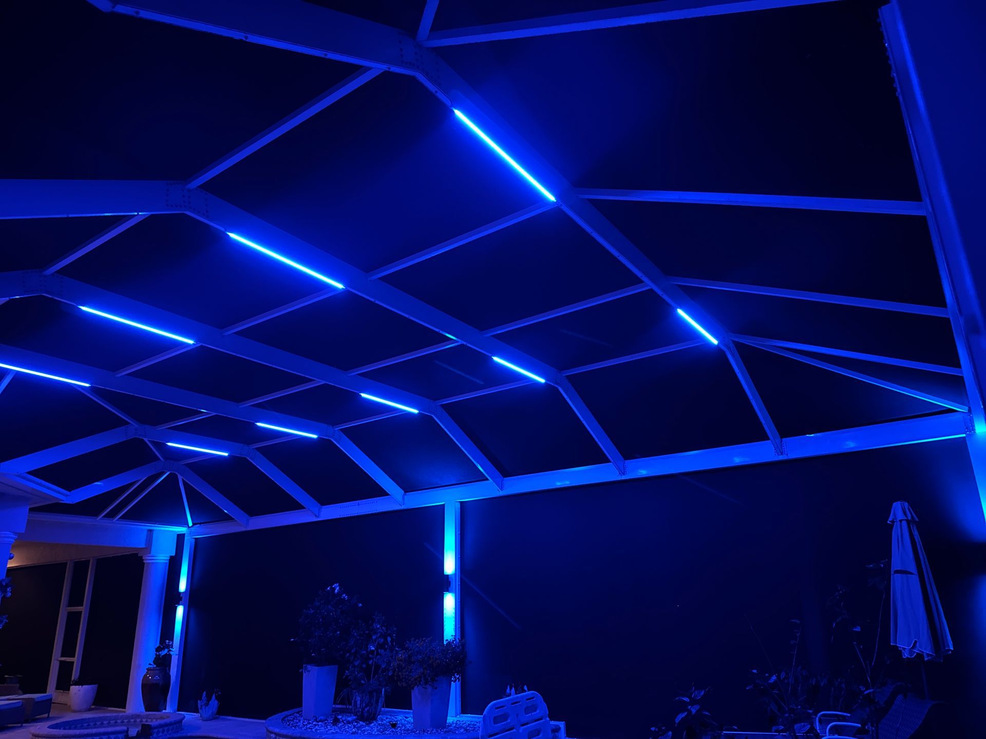 Indoor pool at night with jacuzzi, lounge chairs, and overhead lights.