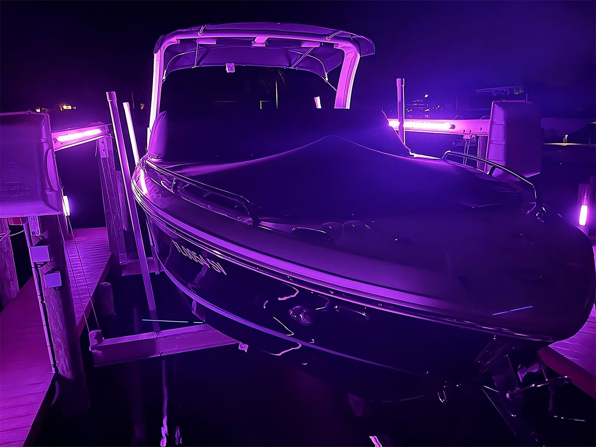 Pool area illuminated with blue lights at night. A covered structure and a dark surrounding.