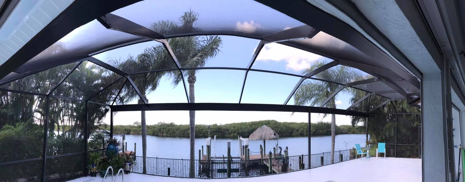 Patio with screened roof overlooking a body of water and dock.