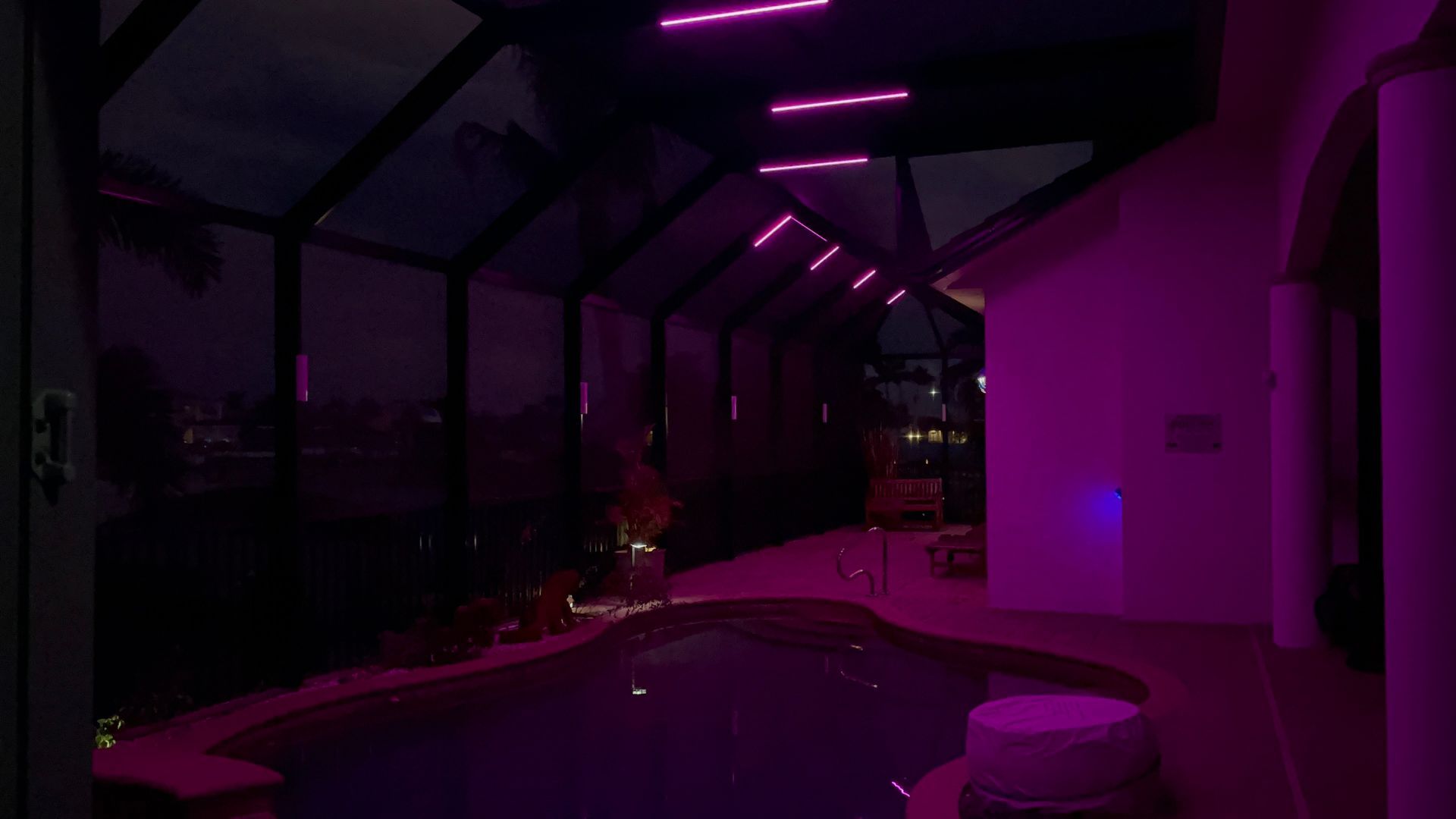 Poolside patio with pink neon lights at night.