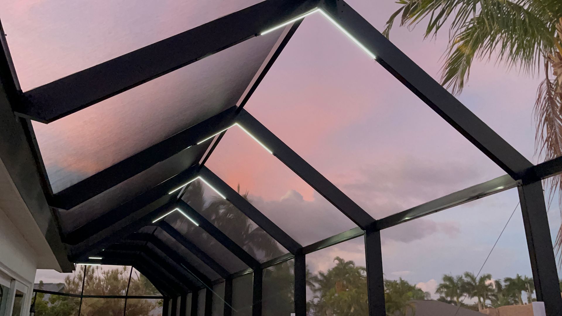 Black-framed patio roof with overhead lights, against a pink and purple sunset sky.